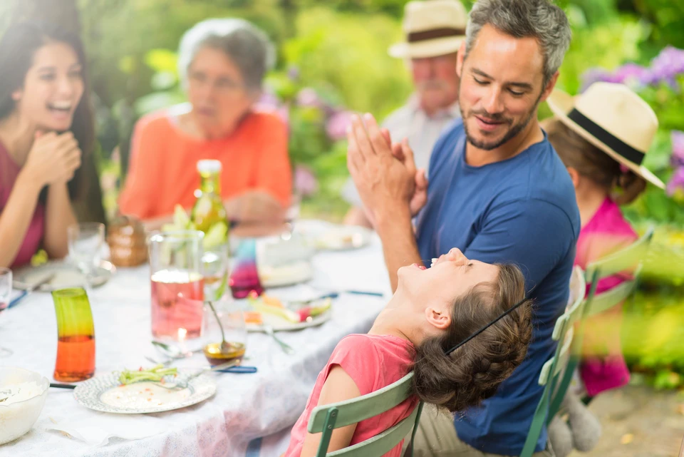Scène extérieure de repas familial dans un jardin fleuri